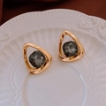 Detail of gold triangle earrings with dark grey crystal on a textured ceramic plate - Simple Hollow Triangle Dark Grey Style