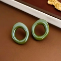 Detail view of irregular olive green resin earrings on vintage aesthetic display - Irregular Geometric Style / Green