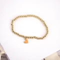 Close-up of golden beaded stretch bracelet featuring a vibrant orange heart pendant - Orange