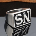 Close-up of silver punk wide band ring with embossed SN letters on a mirror finish - Steel Silver SN