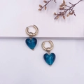 Détail de boucles d'oreilles créoles dorées avec pendentifs en verre bleu en forme de cœur - Bleu Océan