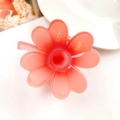 Detailed view of a soft pink hollow frangipani hair claw clip on a white ceramic plate - Clover Orange Red