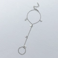 Silberne Handkette mit Stern- und Mondanhänger und Fingerring auf weißer Textur - Silber