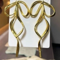 Elegant long golden ribbon bow earrings with a streamlined metallic finish design - Gold