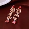 Close-up of golden butterfly earrings with red teardrop crystals on red velvet - Gold-Red (Butterfly Tassel)