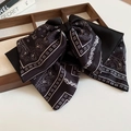 Close-up of black satin bow hair claw clip with white Paisley patterns and geometric dots - Black Hair Claw