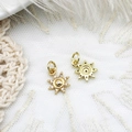Macro detail of gold sunburst charms with micro-paved cubic zirconia on white lace - Sun
