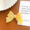 Elegant amber marble acetate bow hair tie with pearl accent on brown leather background - Floral Yellow - Duckbill Clip