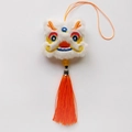 Gros plan du pendentif lion dansant en peluche blanche avec broderie et pompon orange - Dragon de Bon Augure / Blanc