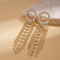 Detailed view of long gold tassel earrings with shimmering crystals on marble - Silver Pin Tassel Style / Gold