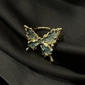 Close-up of gold butterfly ring with blue textured wings on black silk background - Adjustable Open / Gold Metal Blue Matte Butterfly (JZ4285)