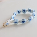 Macro shot of hand-woven blue daisy flower lanyard with a gold spring ring clasp - Light Blue
