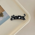 Detalle de la pinza para el pelo de gato con lunares sobre una bandeja de crema - Negro