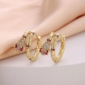 Detailed macro view of gold snake hoop earrings with zircon pavé and red gemstones - Red Eye Snake Scale