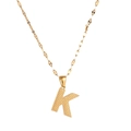 Detail shot of a golden letter K pendant with a textured surface on a delicate chain - Letter K