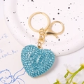 Macro shot of heart-shaped keychain with light blue rhinestones in a ceramic dish - Full Rhinestone Light Blue Heart Pendant