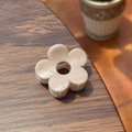 Close-up of cream-colored floral claw clip with a resin finish on a wooden table - Stone Grey