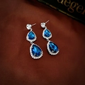 Détail de boucles d'oreilles doubles gouttes en cristal bleu sur fond en soie élégant - Boucles d'Oreilles Goutte d'Eau en Strass Bleu avec Tige en Argent