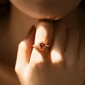 Detail of a luxury gold ring with a red gemstone and pavé diamonds worn on finger - Adjustable Open / Red (KR0042-3)