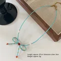 Handmade sky blue beaded necklace with a golden bow pendant and red bead accents - Blue Beaded Bowknot Necklace XL0698