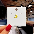 Close-up of a yellow crescent moon enamel pin on a white display card held by hand - 157*Yellow Crescent Moon