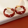 Detail of red fabric-wrapped hoop earrings with white polka dots and gold clasps - Brown