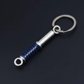 Detail of metal car shock absorber keychain with blue spring on a dark background - Blue Shock Absorber