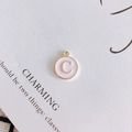 Détail macro du pendentif rond en émail rose avec lettre C dorée et petit anneau - Lettre C