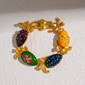 Detail of vintage gold bracelet with colorful enamel egg charms and golden bow accents - Bracelet - Gold