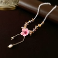 Dettaglio della collana con ciondolo a fiore rosa, perline di cristallo e nappa di perle - Fiore Rosa