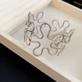 Detail view of a silver-toned hollow flower bangle with polished metallic finish - Arm Cuff / Silver