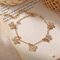 Elegant gold butterfly chain bracelet with adjustable clasp displayed on an open book - Bracelet / Gold