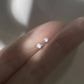 S999 sterling silver stud earrings with small clear cubic zirconia held by hand - White