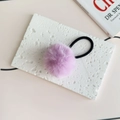 Close-up of light purple plush pom-pom hair tie on a white stone display plate - Purple Pink