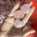 Three natural pink quartz heart stones with golden Lucky engraving held in palm - Lucky