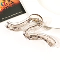 Close-up of a large wave-shaped clear hair claw clip on a ceramic tray with metal spring - 13cm Geometric Wave - Transparent Grey