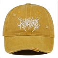 Detailed close-up of distressed yellow cotton cap with white Gothic embroidery and torn fabric - Orange