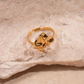 Detalle de un anillo dorado ondulado con circón blanco sobre fondo de piedra natural - Estilo Cuadrado Geométrico Dorado