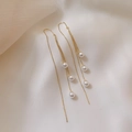 Close-up of elegant gold tassel earrings with white pearls on a soft fabric background - Gold Pearl Tassel Earrings