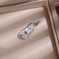 Détail d'une broche violon argentée avec strass clairs dans un coffret à bijoux beige - Violon / Argent - Zirconia Blanc