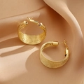 Twisted gold hoop earrings in a woven rope style on a champagne satin background - Woven Texture Hoop Earrings / Gold