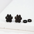 Close-up of minimalist black matte paw print stud earrings on white stone texture - 104 Paw / Black