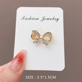 Golden bow brooch pin featuring sparkling white rhinestones and opal heart details - Bowknot Spec (90472)