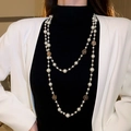 Long double-layer pearl necklace with golden rose flower charms on a model - Hollow Flower Double Layer Long Pearl Necklace Gold