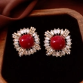 Vista macro di orecchini vintage in zircone rosso e metallo dorato su velluto nero - Lega con Zirconia (Perno in Argento 925) / Rosso Vintage (Base Oro)