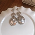 Vista macro de pendientes ovalados plateados con textura martillada en plato - Pendientes - Plata