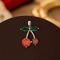 Macro shot of silver cherry pendant with red round gems and green marquise leaves - Silver Green Leaf Red Zirconia