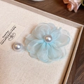Dettaglio macro di un fiore in organza azzurro con una perla centrale su sfondo neutro - Blu