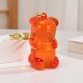 Gros plan d'un ours en résine orange translucide avec porte-clés en métal doré sur pierre - Chaîne Or Clair + Ours / Rouge