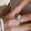 Minimalistischer, herzförmiger Ring in glänzendem Silber am Zeigefinger getragen - Puffy Herz Silber Ring